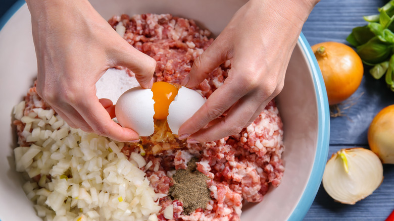 woman adding eggs to meatloaf 