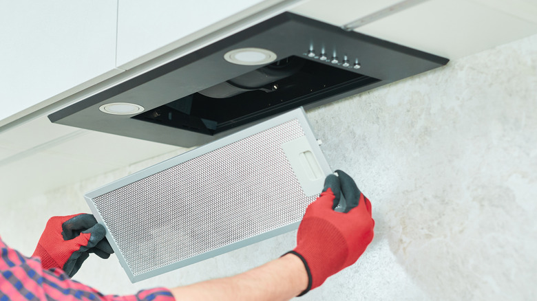 Person removing filter grate from range hood