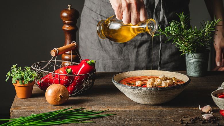 pouring oil into a bowl of soup