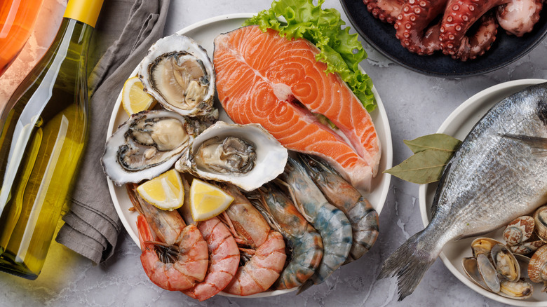 Seafood platter with shrimp, oysters, and salmon, surrounded by wine, octopus, and fish