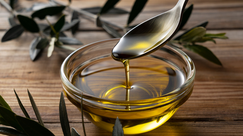Spooning olive oil in a clear bowl