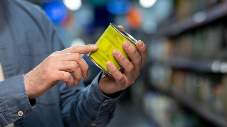 Someone reading labels on a canned food item
