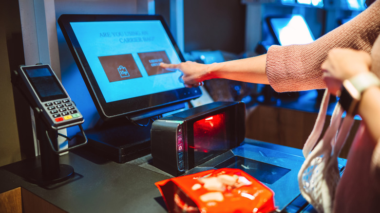 Someone interacting with a self checkout kiosk at a grocery store