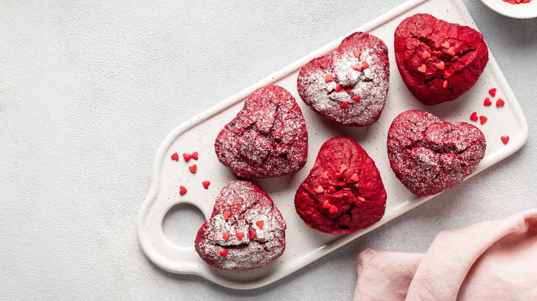 Red heart-shaped cupcakes topped with powdered sugar and red heart sprinkles