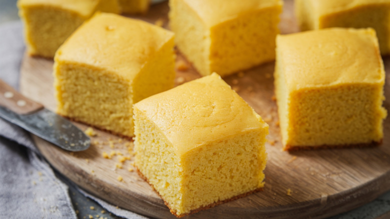 Cornbread cut into squares on wooden board.