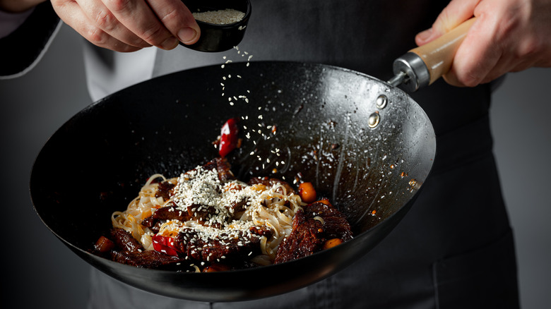 person prepping a meal in a wok