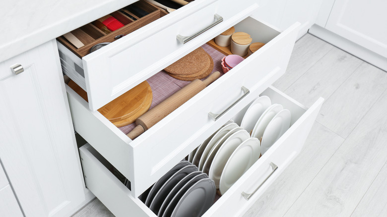 Three open drawers with cooking supplies in white kitchen