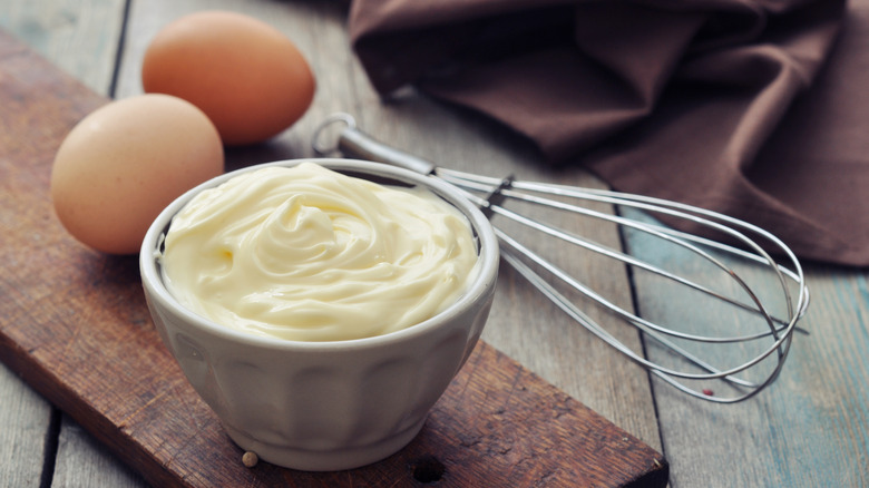 Mayo in a bowl next to eggs and a mixer