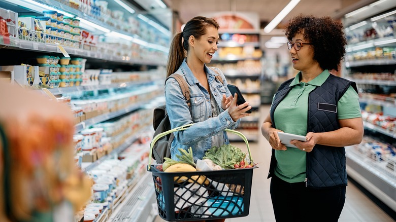 customer showing a grocery store employee a coupon on her smartphone