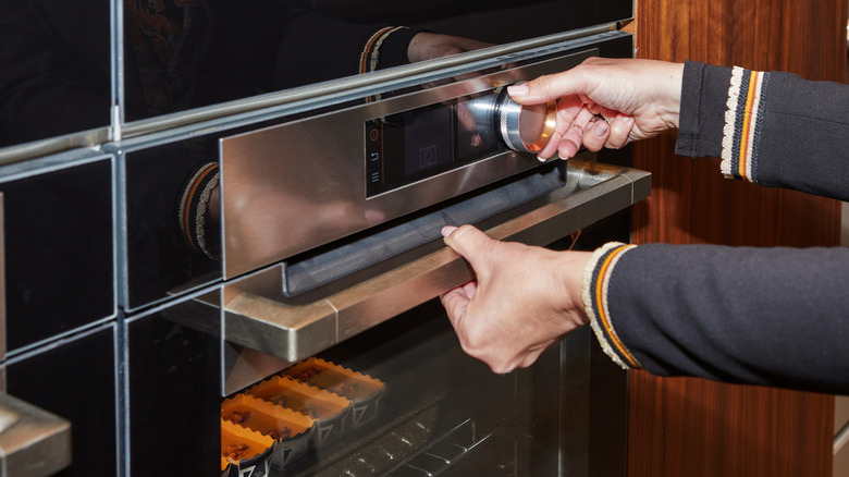 Person adjusting temperature on oven