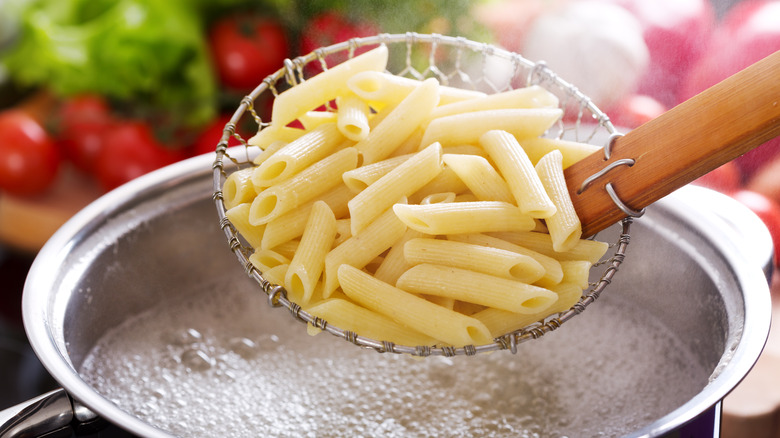 Penne in strainer above boiling pot
