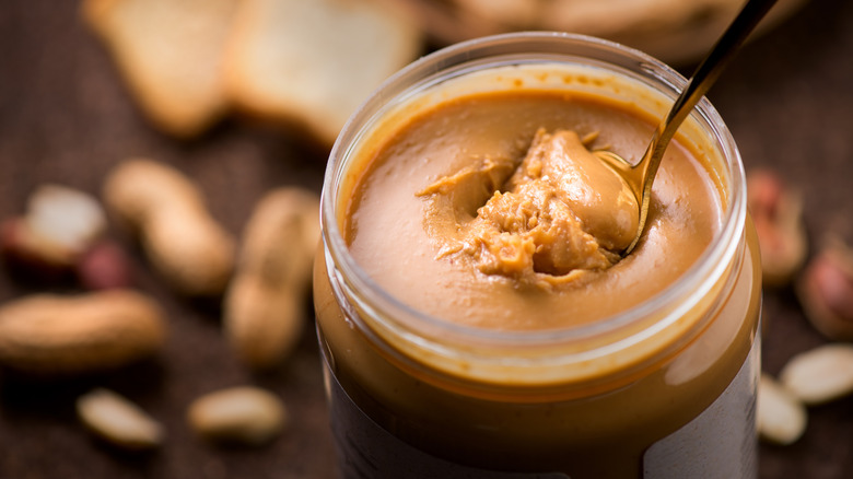 Unlabeled jar of peanut butter with a spoon inside
