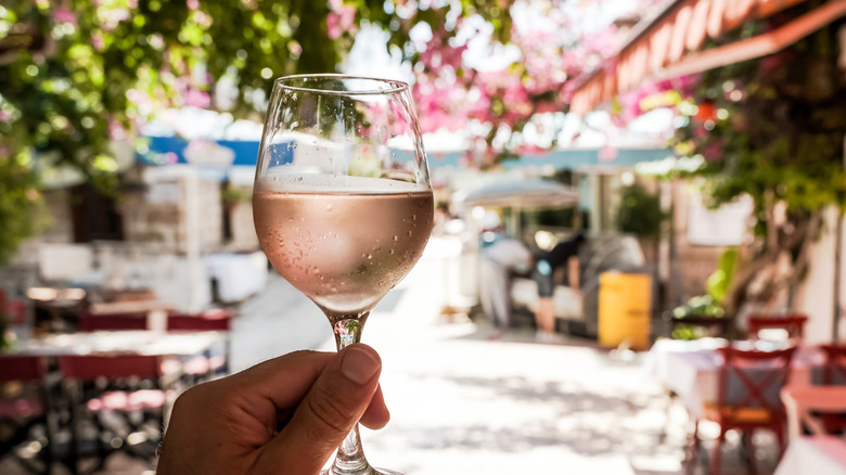 person holding cold glass of rose wine 