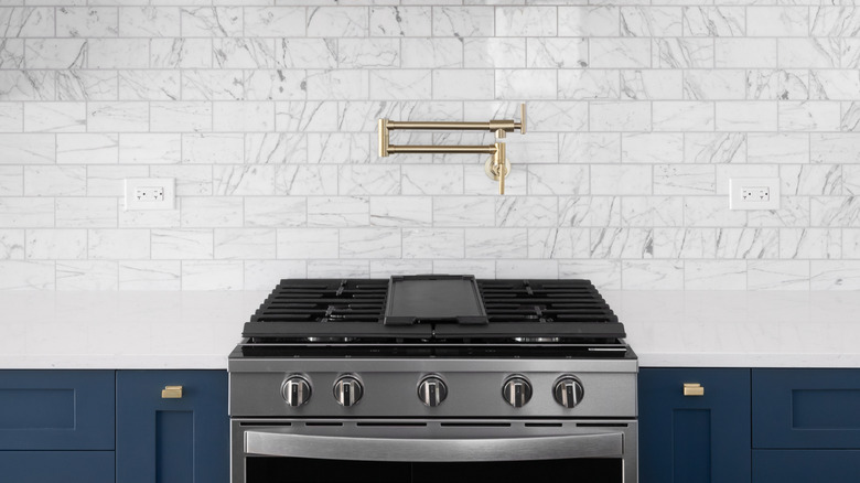 Pot filler faucet built into the backsplash above a gas range with lots of countertop space on either side