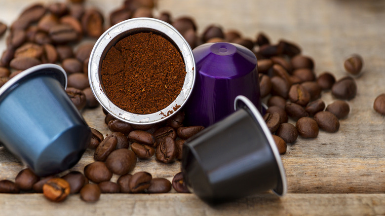 colorful espresso and coffee pods with coffee grinds on a wood background