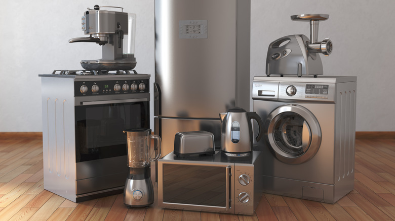 Variety of stacked kitchen appliances in an empty, wood-floor room