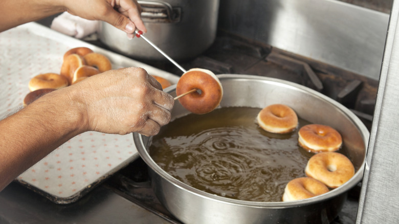 person frying donuts in hot fat