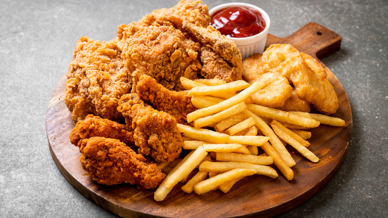 Crispy fried chicken with chicken nuggets and french fries on a wood board