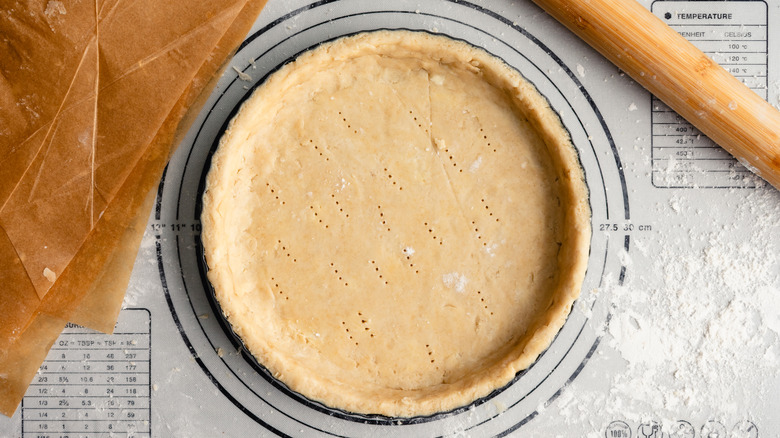 unbaked pie crust dough with rolling pin and parchment