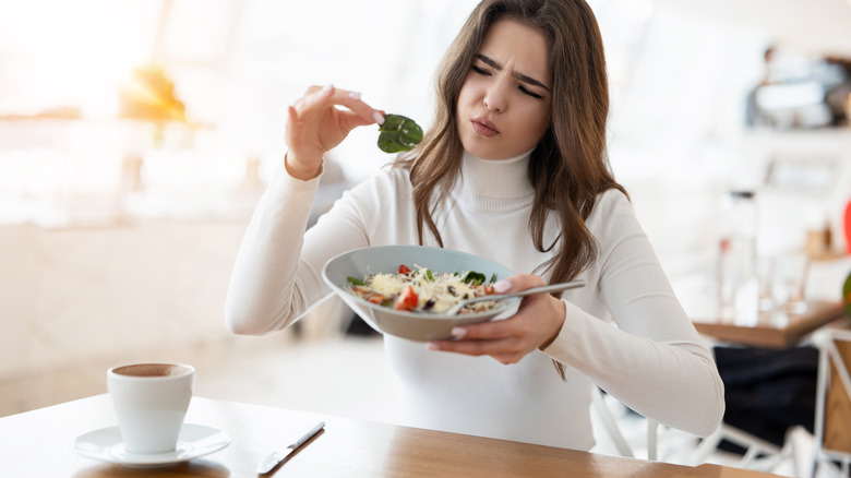 young woman appearing unsatisfied with food at restaurant
