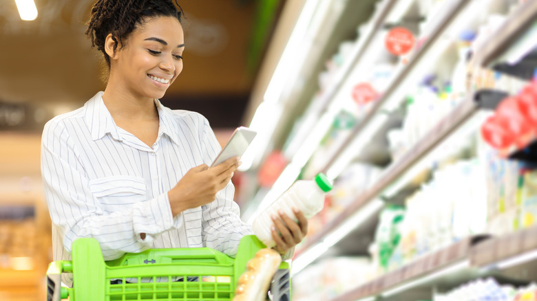 woman grocery shopping with phone coupon