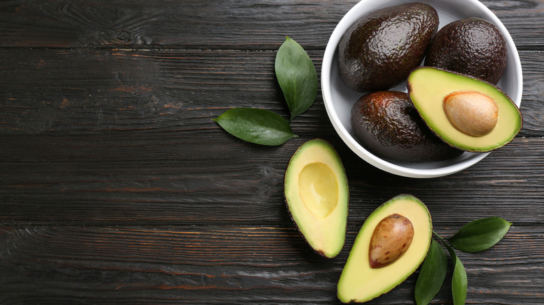 Avocados in bowl on wood