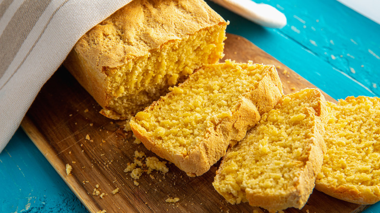 Slices and loaf of homemade cornbread on a wood cutting board