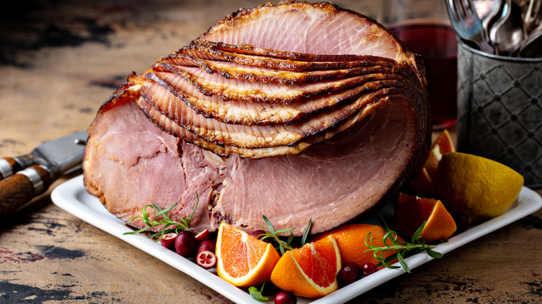 sliced spiral ham on serving platter with orange wedges