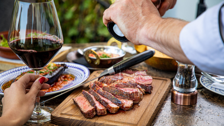 Wine and grinding salt over steak 