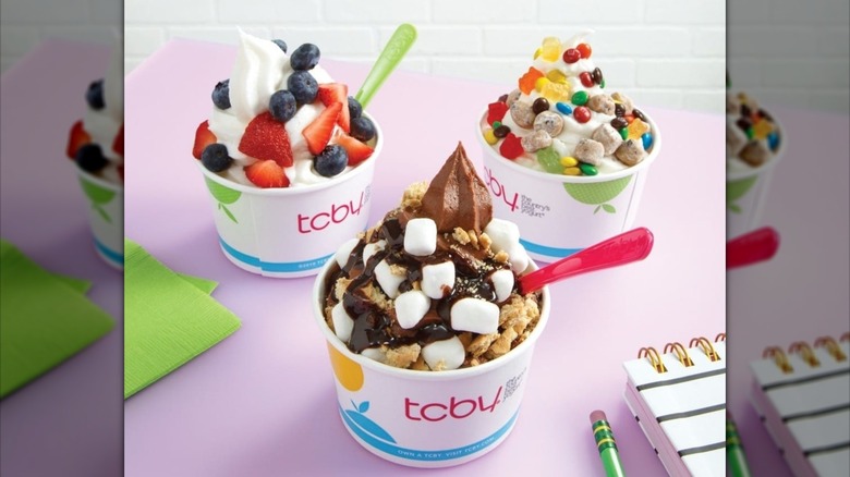 Three cups of TCBY frozen yogurt with toppings