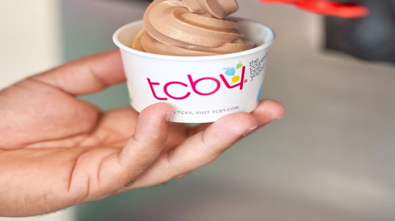 Hand serving up chocolate frozen yogurt in TCBY cup