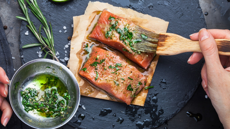 person brushing marinade on salmon