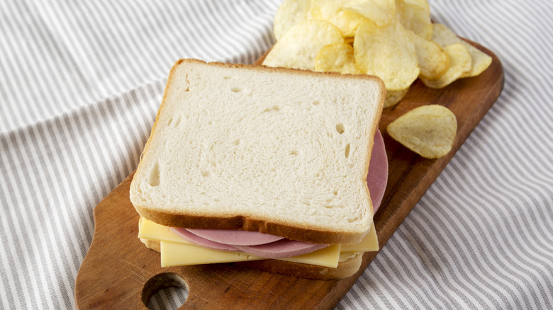 Classic bologna sandwich on white bread with side of chips