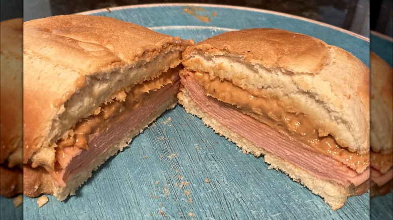 Peanut butter and bologna sandwich cut in half on a blue plate