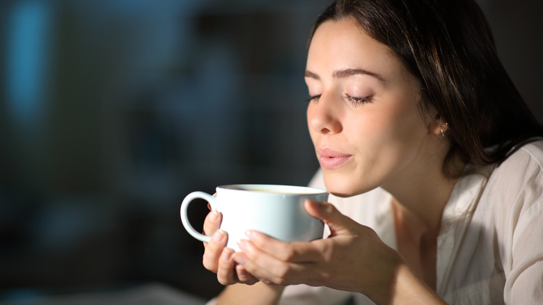 Woman blowing on coffee cup 