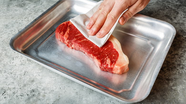 Defrosted steak on aluminum tray