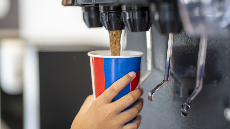 Person dispensing soda into fast food cup