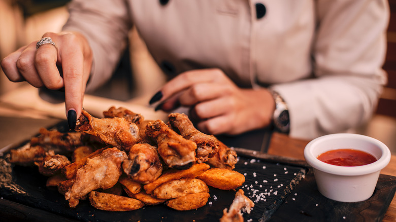 hand picking up chicken wing from pile