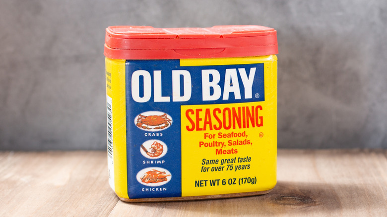 Container of Old Bay Seasoning on a wood table and gray background.