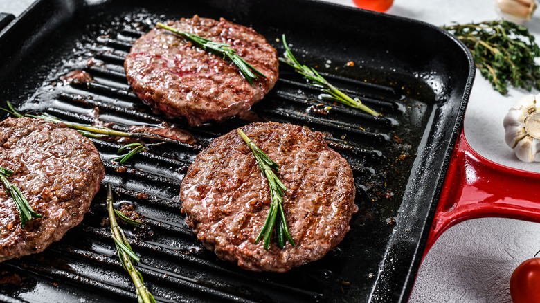Beef patties sizzling on pan