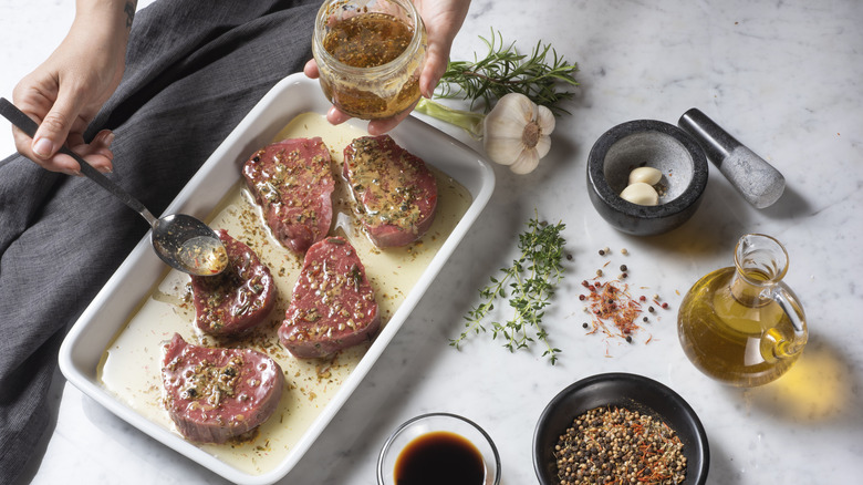 Hand applying marinade to steak