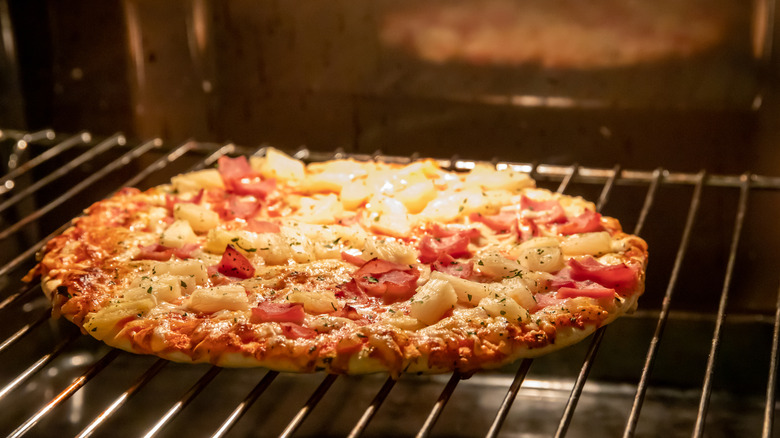 Frozen pizza cooking in oven directly on rack.