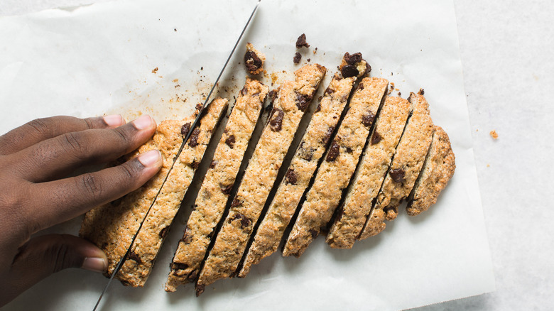 Hand slicing biscotti before a second bake