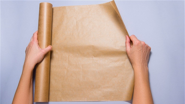 Hands unrolling parchment paper