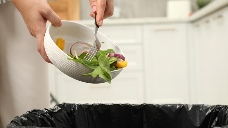 throwing food into trash in kitchen