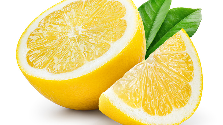 Sliced lemons near green leaves