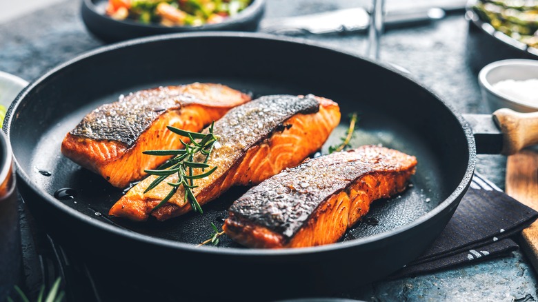 Crispy skin salmon fillets frying on pan