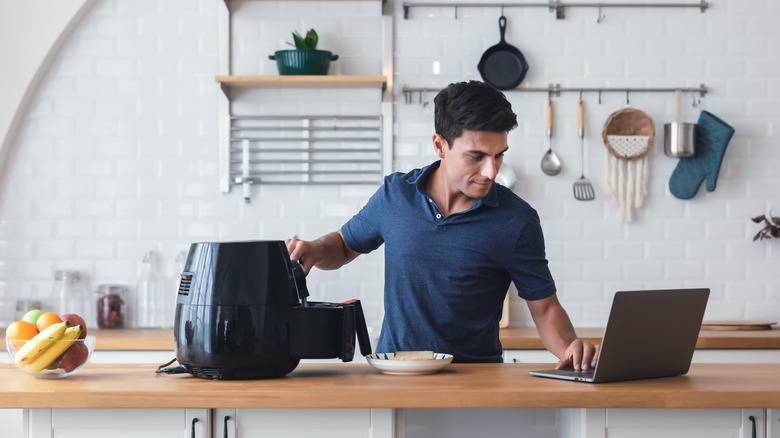 Man using an air fryer to dry fruit