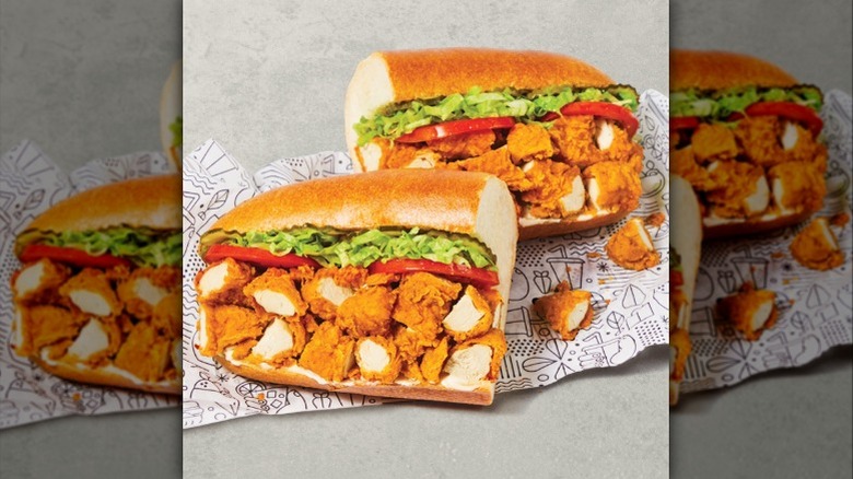 Diced fried chicken tenders on a sub roll with tomatoes, shredded lettuce, and pickles