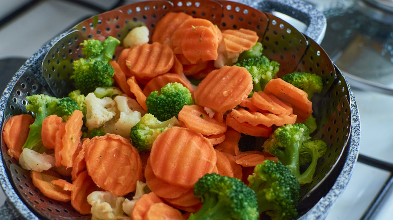 Steamed broccoli, carrots, and cauliflower in a metal steamer basket